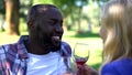 Pleased couple enjoying beverage on picnic, romantic date, wine traditions