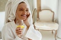 Pleased european girl drink lemonade in bathrobe
