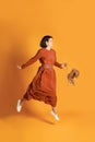 Pleased european girl jumping on yellow background. Studio shot of pretty young woman in romantic summer dress