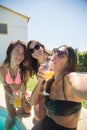 Pleased female friends taking selfie at poolside