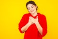 Pleased female standing in red sweater in the yellow studio.