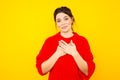 Pleased female standing in red sweater in the yellow studio.