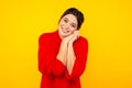 Pleased female standing in red sweater in the yellow studio.