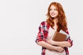 Pleased ginger woman in shirt holding books and looking away