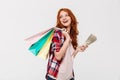 Pleased ginger woman in shirt holding packages on shoulder