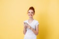 Pleased ginger woman in t-shirt holding smartphone in hands