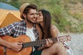 Pleased guy play on guitar to girl who is kissing him Royalty Free Stock Photo