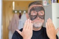 Pleased man using a cosmetic face mask gesturing Royalty Free Stock Photo