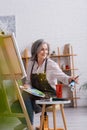 pleased mature artist holding paintbrush and