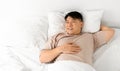 Pleased Middle Aged Asian Man Lying In Bed Royalty Free Stock Photo