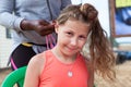 Pleased pretty girl has cornrow making Afro American female hands, looking at camera