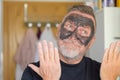 Pleased man using a cosmetic face mask gesturing Royalty Free Stock Photo