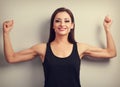 Pleased strong fit woman showing muscle biceps with happy smiling. Toned vintage portrait