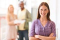 Pleased to be at work. Smiling young businesswoman dressed casually for work and standing with her arms folded. Royalty Free Stock Photo