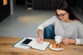 Pleased woman writing down notes while drinking coffee with croissant Royalty Free Stock Photo