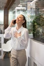 Pleased young business woman talking on mobile phone at office. Royalty Free Stock Photo