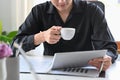 Pleased businessman drinking coffee and checking financial data on digital tablet. Royalty Free Stock Photo