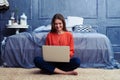 Pleased young girl sitting cross legged and working on a laptop Royalty Free Stock Photo