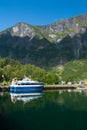 Pleasure boat at sea pier on mountain landscape in Flam, Norway. Small ship in sea harbor with green mountains