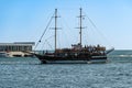 Pleasure double-deck yacht `Gloria` sails to city pier on embankment of Gelendzhik. Tourists on upper and lower decks of yacht.