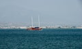 Pleasure yacht with tourists moves in emerald waters of Aegean Sea. In the background is ancient city of Fethiye. Blurred backgrou Royalty Free Stock Photo