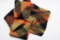 Pleats on fabric, knitted material of orange black green color, folds of scarf on the white background.