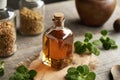 Plectranthus amboinicus tincture in a glass bottle on a table