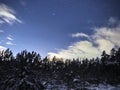 Pleiades open star cluster on night sky and clouds over winter forest Royalty Free Stock Photo