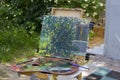 Plein air in nature. Canvas on sketchpad, a palette with used paints. Royalty Free Stock Photo