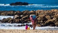 Holidaymaker carries baby on her back on the beach