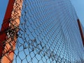 Plexus wire. Metal mesh netting attached to a pole. Part of the fence on the sports ground. In the background is a blue sky. Royalty Free Stock Photo