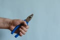 Pliers with blue dielectric grips in a male hand