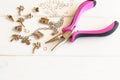 Pliers, chain, metal rings and pendants on a white wooden background. How to do yourself metal bracelet