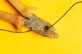 Pliers cuts a black wire on yellow background. pliers with orange handles. work tool Royalty Free Stock Photo