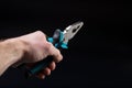 Pliers in hand. Hand of master holding pliers on black. Hand with pliers with copy space Royalty Free Stock Photo