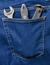 Pliers, nippers, wrench in the pocket of classic blue jeans.