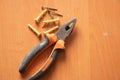 Pliers and self-tapping screws lie on a dirty wooden table, repair Royalty Free Stock Photo