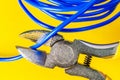 Pliers tool cutting blue electric wire closeup on a yellow background Royalty Free Stock Photo