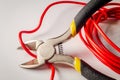 Pliers tool cutting red electric wire closeup on a gray background Royalty Free Stock Photo