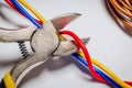 Pliers tool cutting red electric wire closeup on a gray background Royalty Free Stock Photo