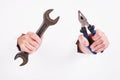 Pliers and wrench in the hand of a girl. Symbol of hard work, feminism and labor day. Isolate on white background