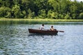 Young couple, a guy and a girl, are sailing in a wooden boat on the Plitvice Lakes and taking pictures of themselves against the Royalty Free Stock Photo