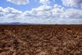 Plough plowed brown clay field blue sky horizon