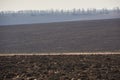 Ploughed field in spring. Hills and forest on horizon. Clear sky