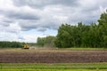 Ploughing Tractor At Field Cultivation Work. machine plows the field, harrows and cultivates the soil for sowing grain