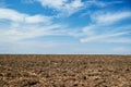 Plowed field and blue sky, soil and clouds of a bright sunny day - concept of agriculture Royalty Free Stock Photo