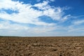 Plowed field and blue sky, soil and clouds of a bright sunny day - concept of agriculture Royalty Free Stock Photo