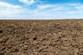 Plowed field and blue sky, soil and clouds of a bright sunny day - concept of agriculture Royalty Free Stock Photo