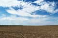 Plowed field and blue sky, soil and clouds of a bright sunny day - concept of agriculture Royalty Free Stock Photo