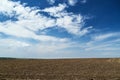 Plowed field and blue sky, soil and clouds of a bright sunny day - concept of agriculture Royalty Free Stock Photo